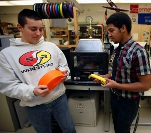 Photo by Tracy Klimek/New Jersey Herald - Newton High School students junior Robert Borgognoni, left, and senior Justin Hermann, right, hold prototypes of handles for a locker as they stand if front of 3D printers on Thursday December 18, 2014, in teacher Brian Bennington's Advanced Principal Design class in the school.