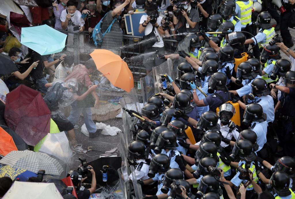 Riot police use pepper spray against protesters after thousands of people block a main road to the financial central district outside the government headquarters in Hong Kong.