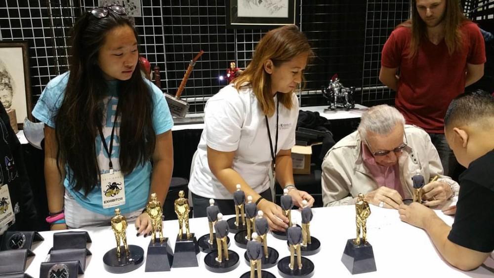 Stan Lee signing his mini-me statues.