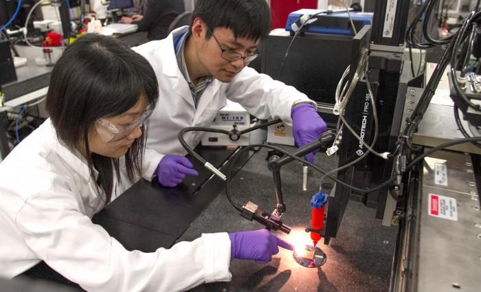 LLNL material and biomedical scientist Fang Qian (left) and engineer Cheng Zhu demonstrate a direct ink writing 3D printer they used to manufacture supercapacitors out of a graphene-based aerogel. Photos by Julie Russell/LLNL