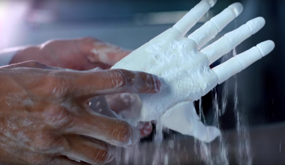 The prosthetic hand emerging from the nylon powder used to make it.