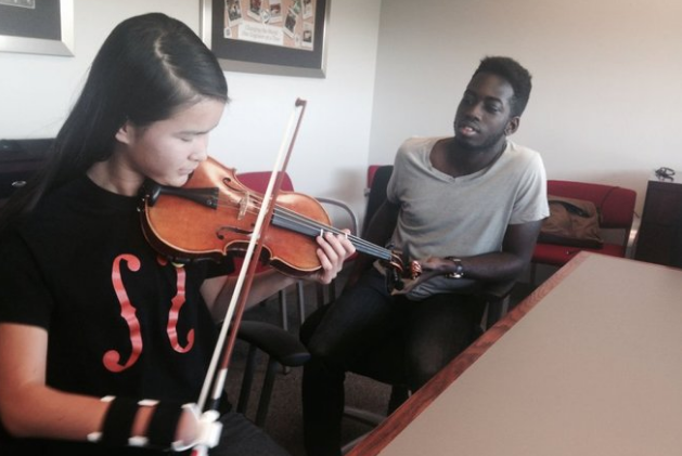 Sarah plays the violin using the prosthetic designed by Oleseun Taiwo. (Photo: Denise Crosby)