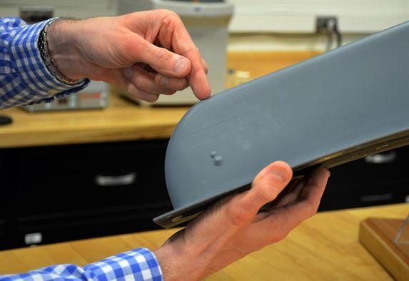 Dr. Dan Berrigan points to an embedded antenna on an MQ-9 aircraft part made possible through functional applications of additive manufacturing. Flexible circuits, embedded antennas and sensors are just a few of the potential manufacturing capabilities his team is exploring using additive technology. (U.S. Air Force photo/Marisa Alia-Novobilski)