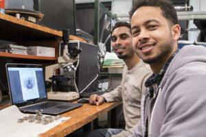 Tri-D Dynamics LLC co-founders Deepak Atyam (left) and Alexander Finch work with components and a diagram of one of their engines. They want to produce tomorrow’s rocket engines using 3-D printers. (Purdue Research Foundation photo/Oren Darling)