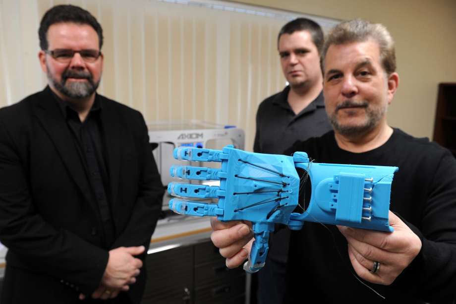 Bernie Richfield, right, president of the board of Access Independence, holds a prosthetic hand made on a 3D printer in Stratford, Conn. Jan. 24, 2017. Richfield is seen here with vice president Jack Heslin, left, and operations director Joe Ecker. [Image: Ned Gerard / Hearst Connecticut Media]