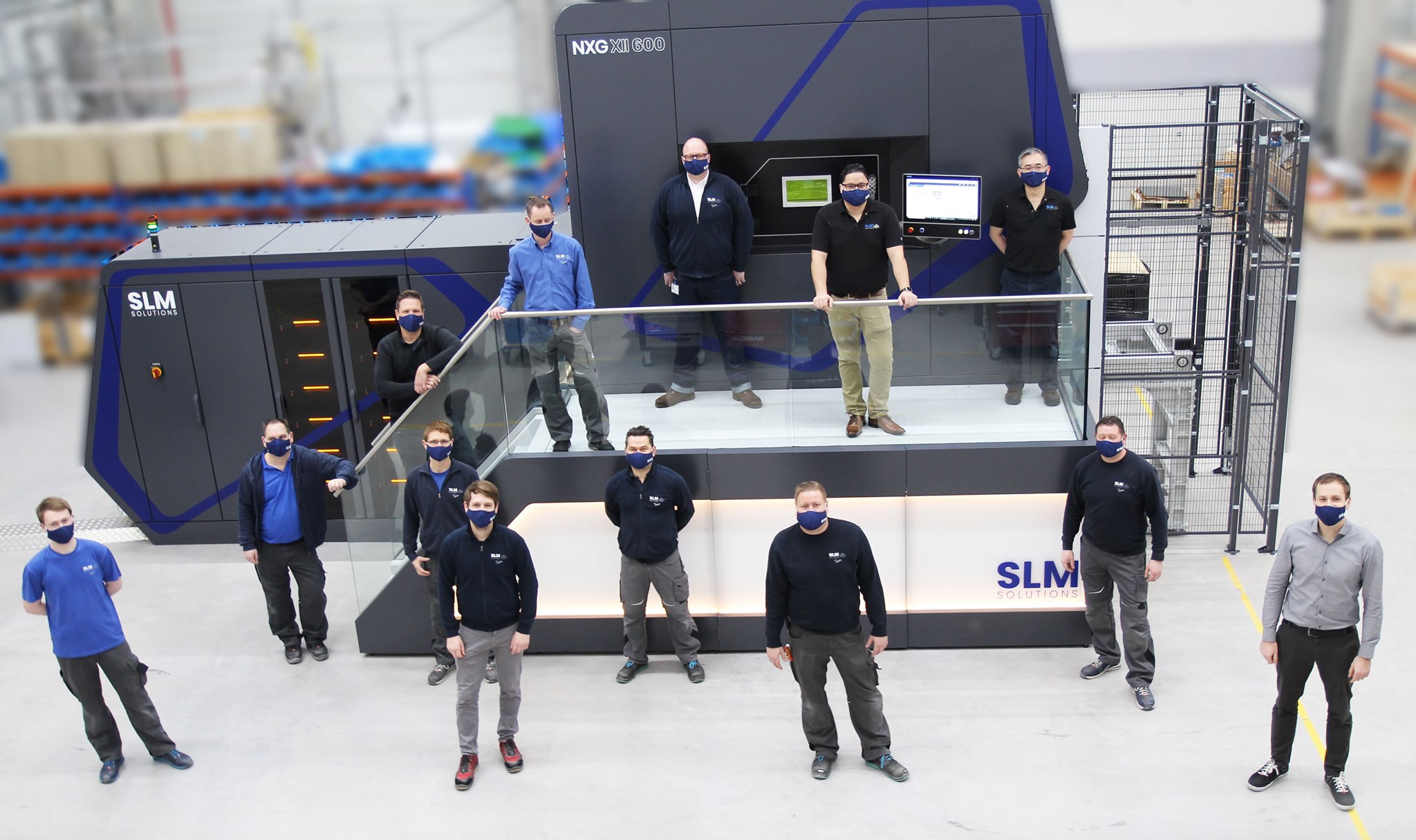 The SLM Solutions team gathered around the new NXG XII 600 system.