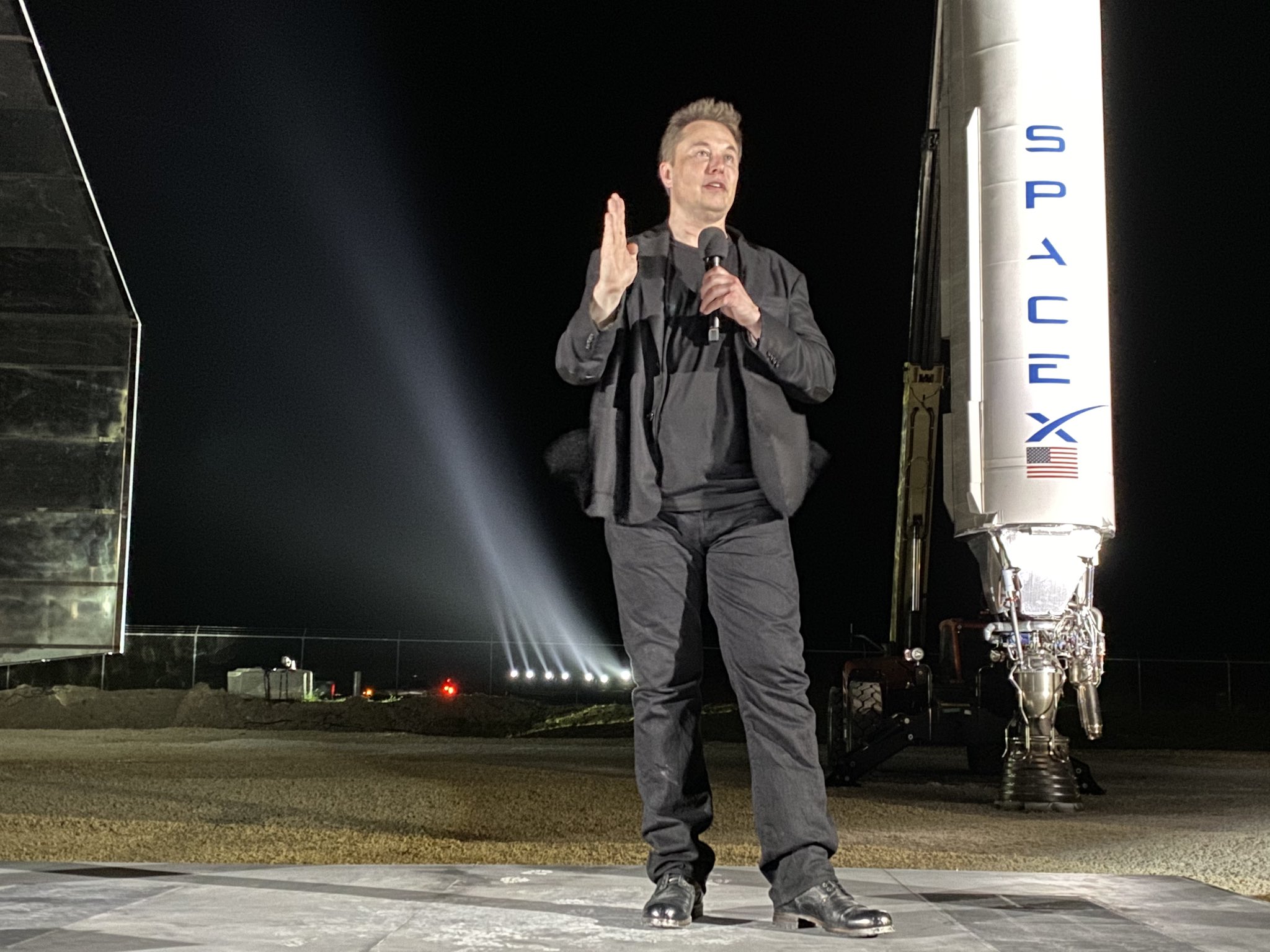 Elon Musk presenting in front of Starship MK 1 and Falcon 1. 