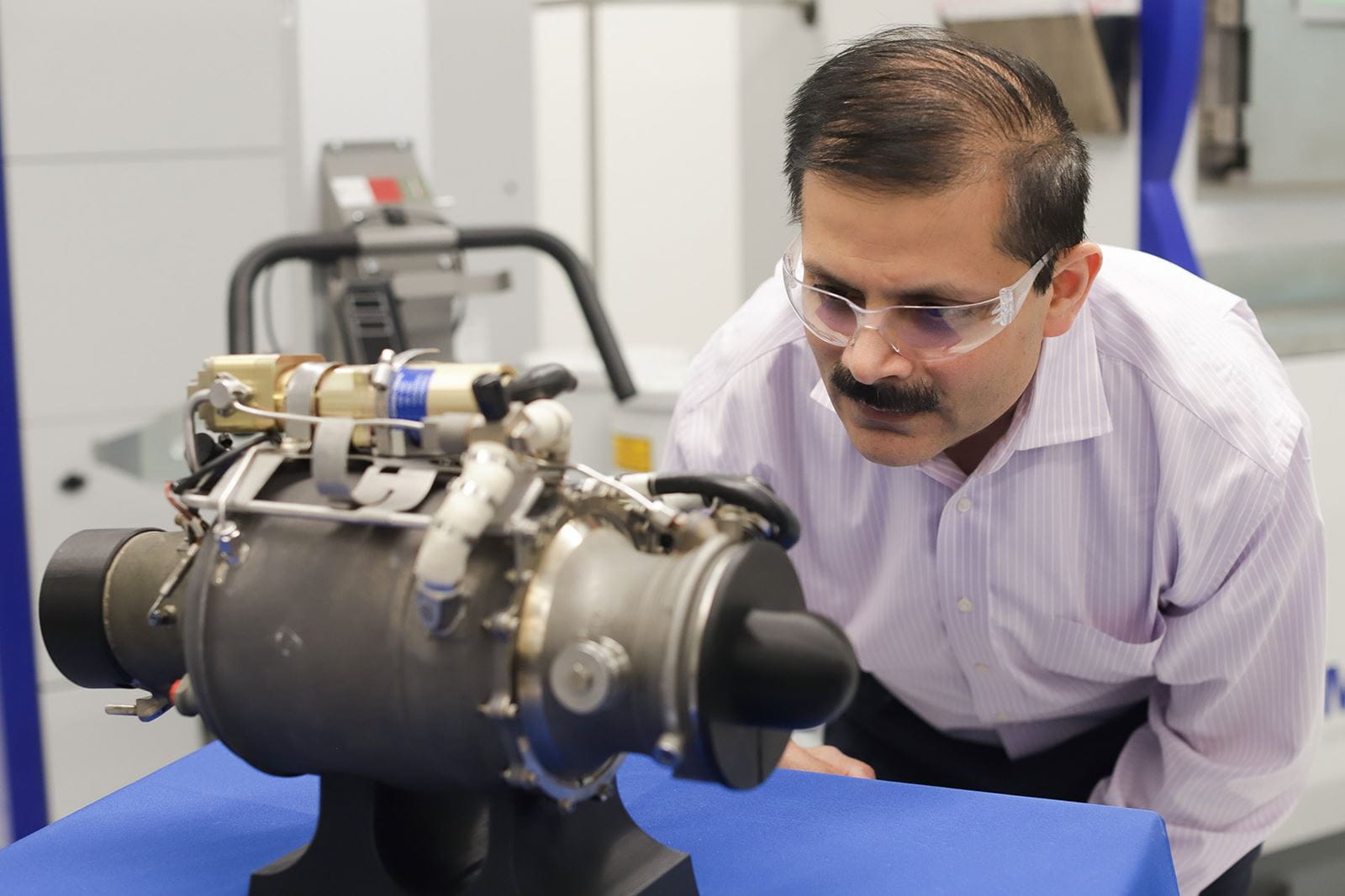 Venkat Vedula, executive director of the Raytheon Technologies Additive Manufacturing Process and Capability Center, examines a small turbojet engine with a 3D printed main body